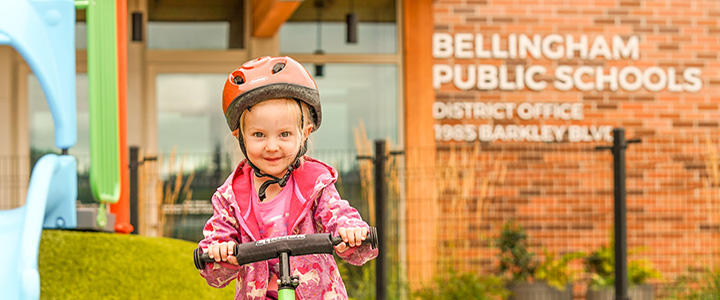 little girl on a scooter in front of the early childhood district office