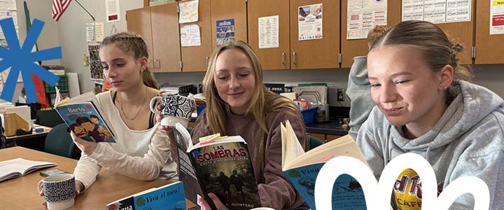 Three girls reading books at a table
