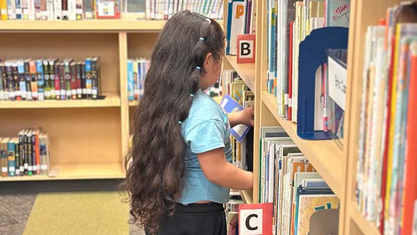 little girl picking out a library book